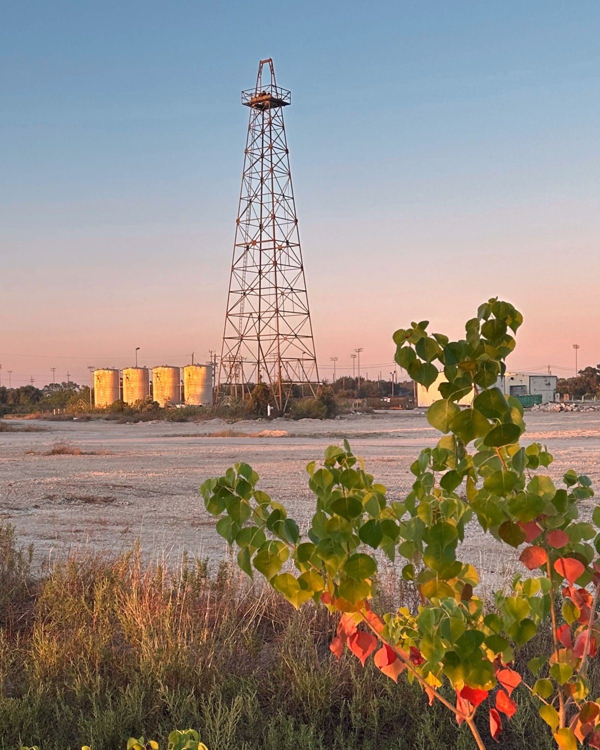 The historic Gasmer derrick and storage tanks at dusk, with fall color in the foreground
